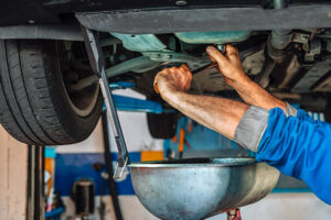 Auto mechanic performing an oil change on a car in a repair shop